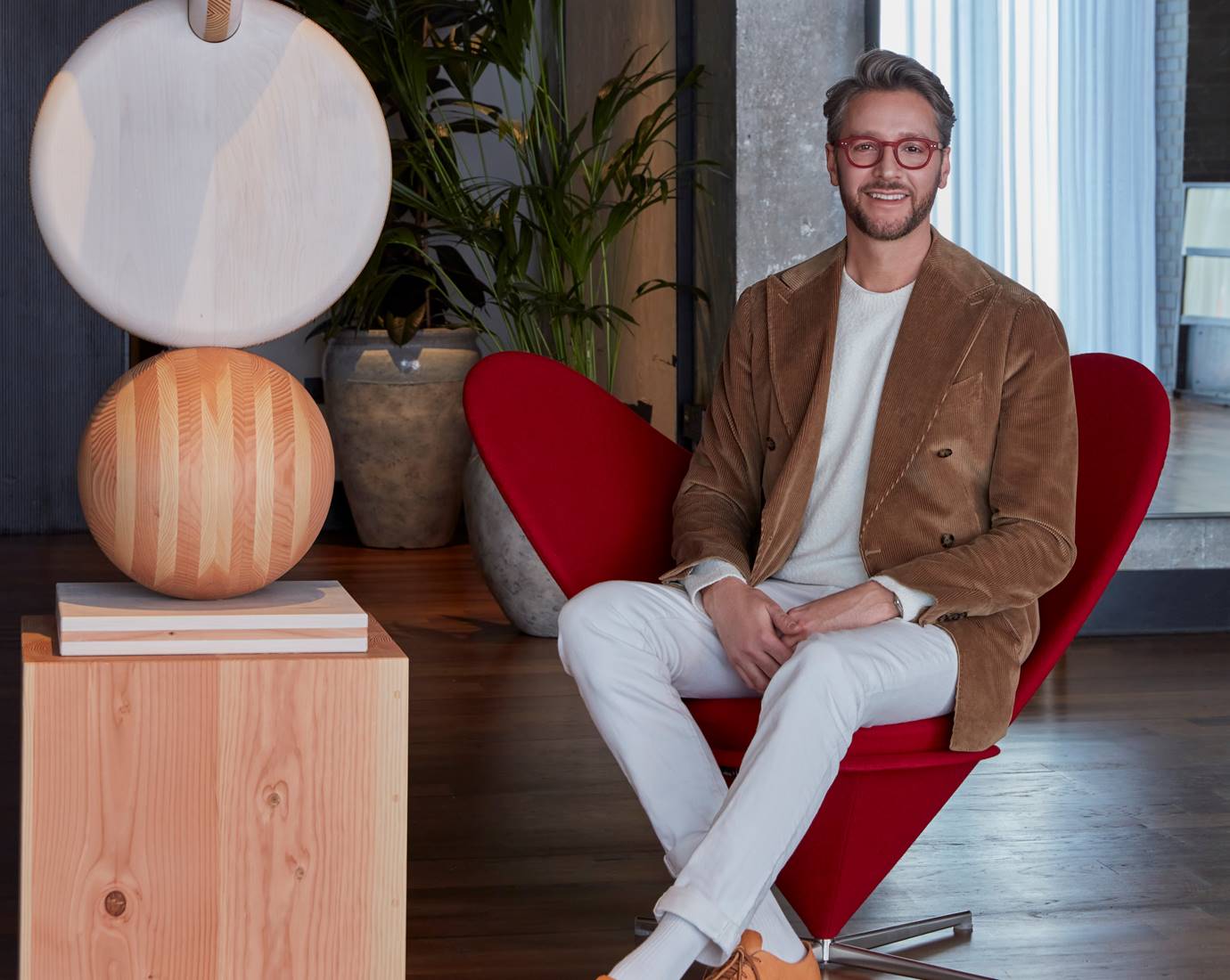 Professional photo of Jacu Strauss sitting in a red designer armchair.