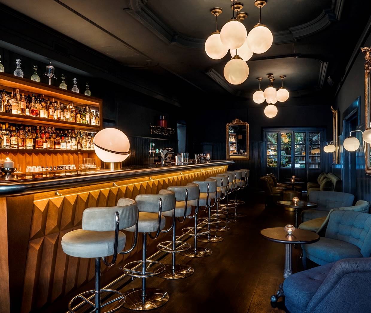 A sophisticated hotel bar with dark wood accents, plush seating, and warm lighting.