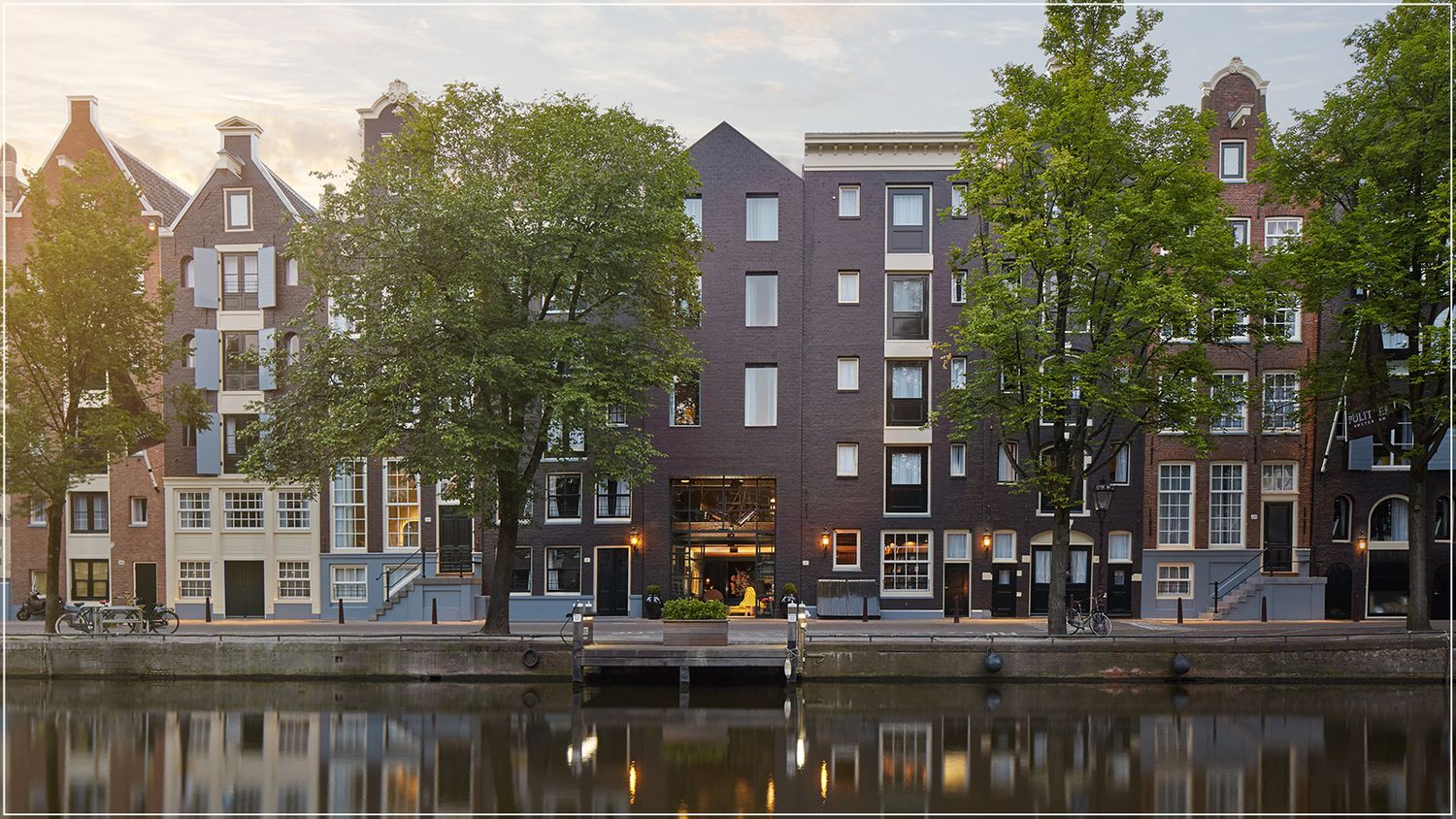 Classic hotel facade in Amsterdam with brick exteriors and a scenic canal view in a charming urban setting.