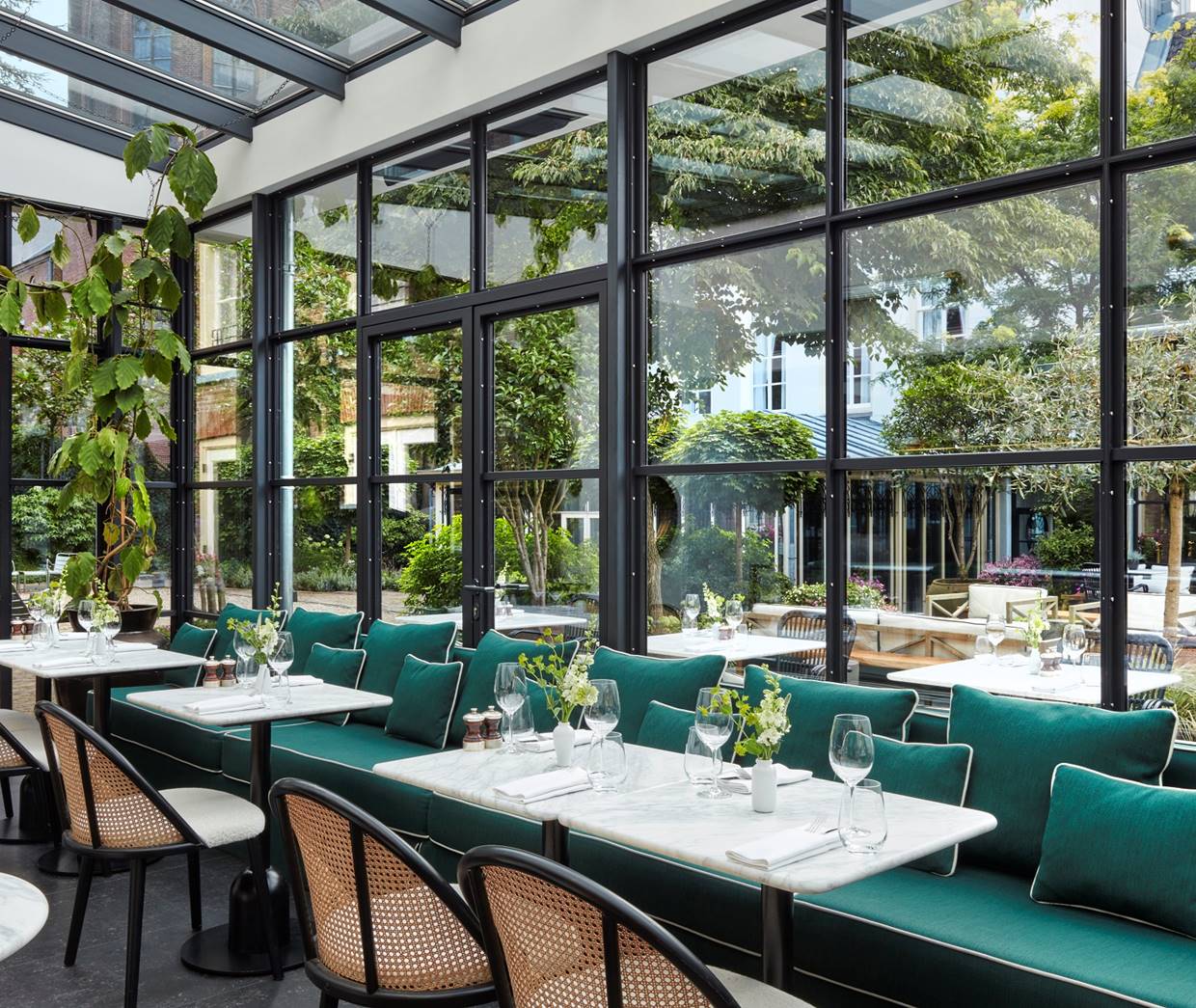 A spacious hotel restaurant featuring a large glass wall that offers a view of the surrounding landscape.