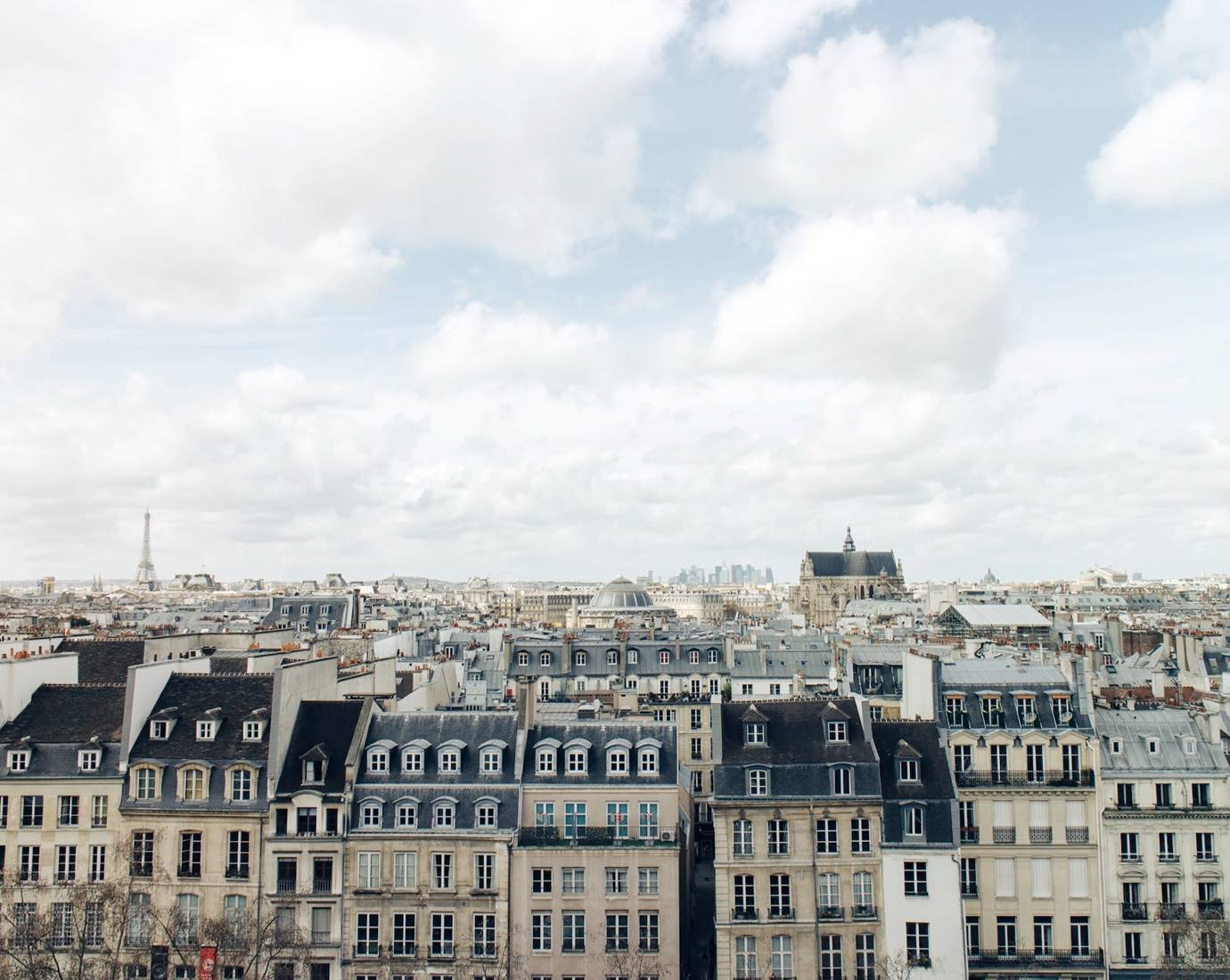 Aerial view of a cityscape in Paris with a prominent central building under a cloudy sky.