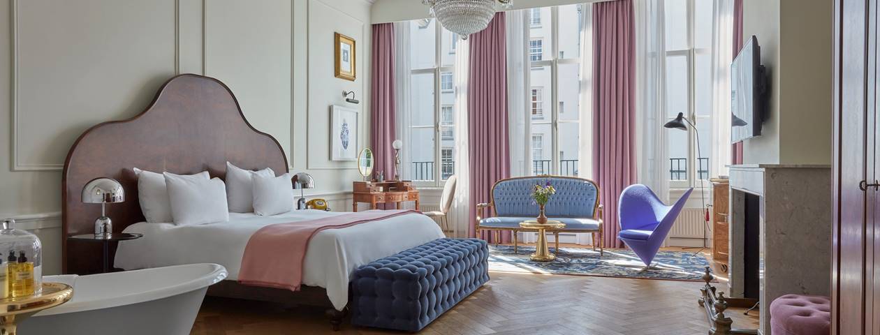 A luxurious suite with classic decor, elegant furnishings, and large windows offering natural light.