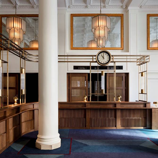 Beautiful wooden reception desk area at Riggs DC in Washington with a marble column and a large clock.