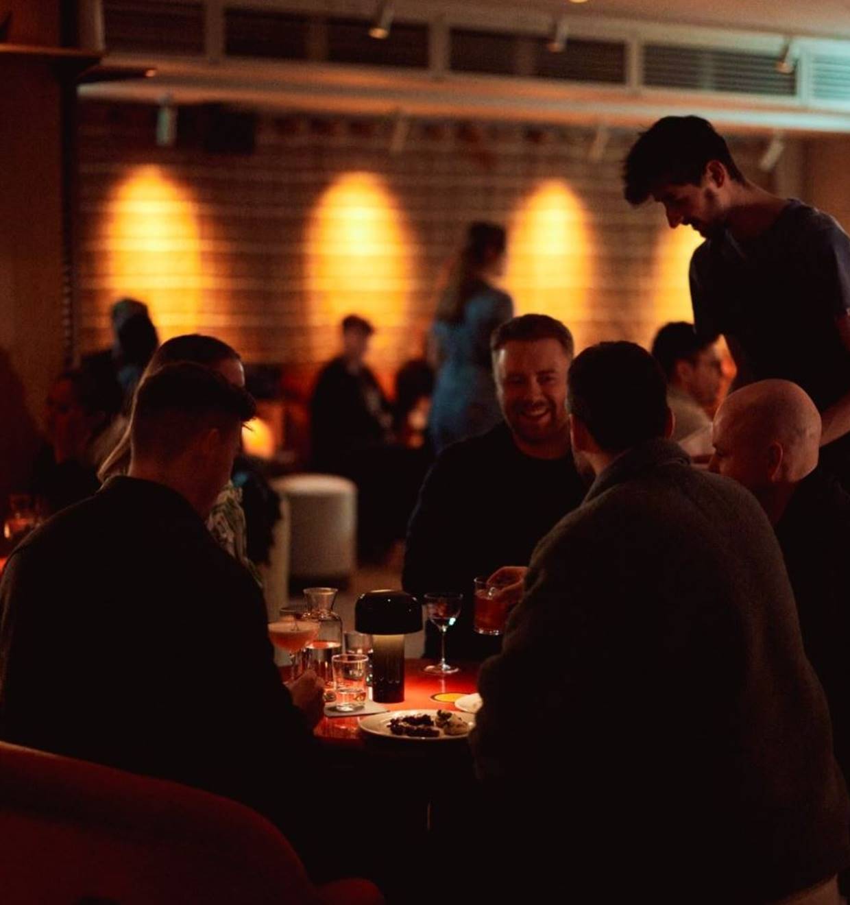 A cozy, dimly lit lounge with plush seating, dark wood accents, and an intimate atmosphere.