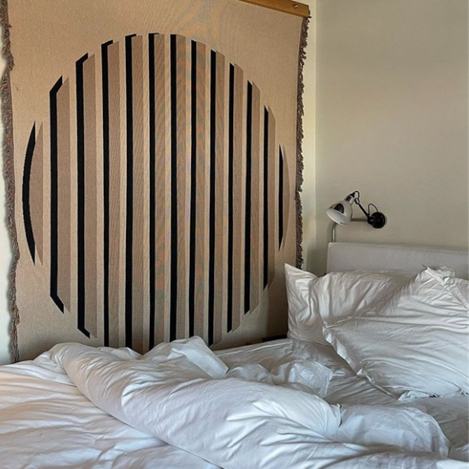Stylish and modern wall cover by a bed in a hotel room.