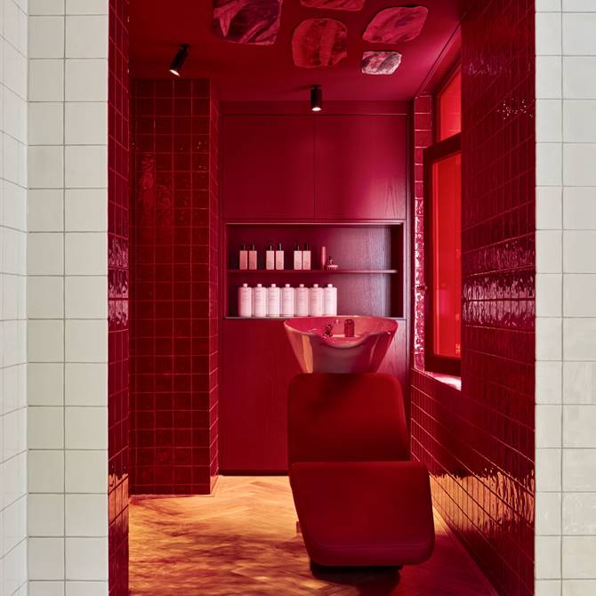 Red tiled salon shampoo station with product bottles on shelves.