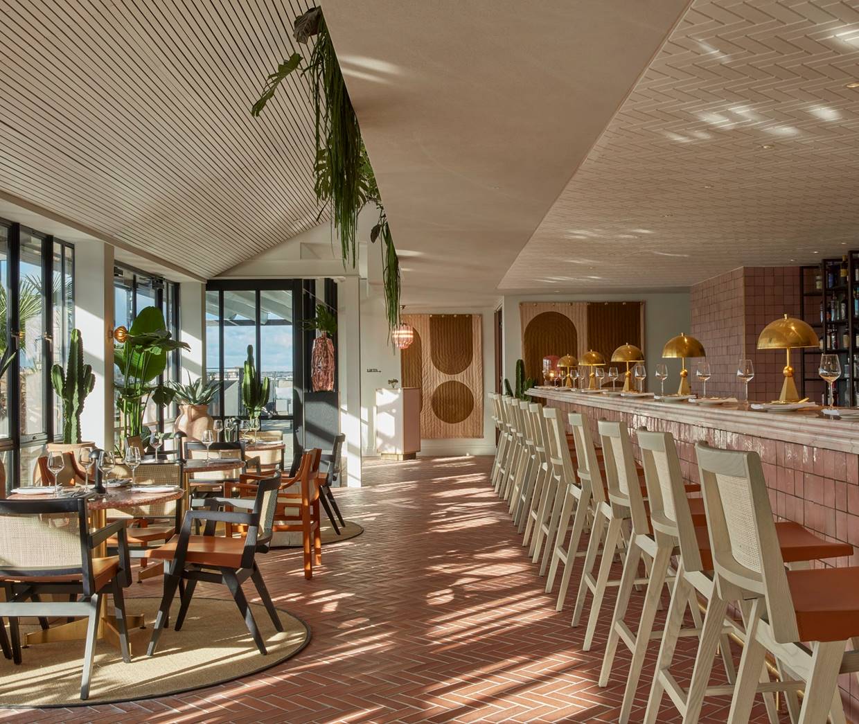 Stylish restaurant and bar area in OHS London with ample light, cacti, light pink colours and wooden furniture.
