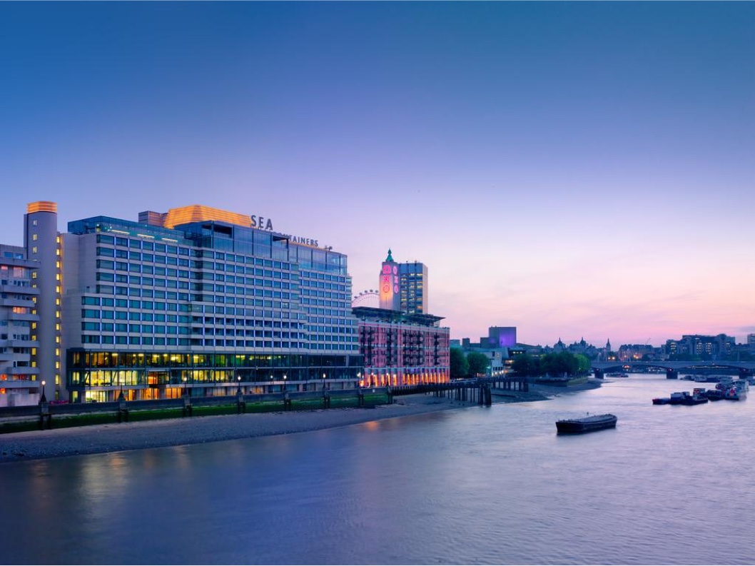 Scenic view of Sea Containers Hotel at sunset along the Thames River, with illuminated windows and a serene atmosphere.
