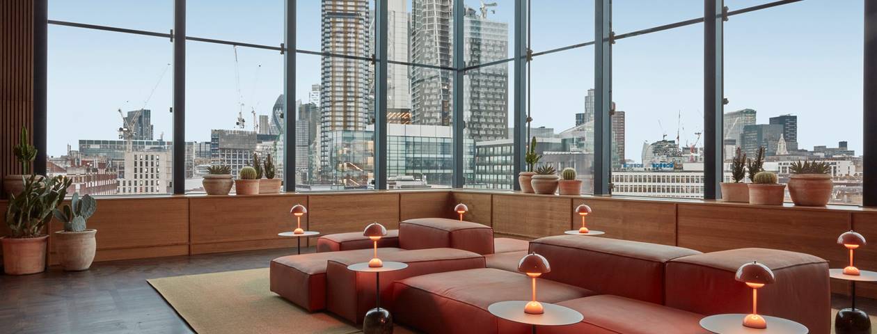 A spacious hotel lobby with expansive windows showcases a stunning view of the bustling city outside.