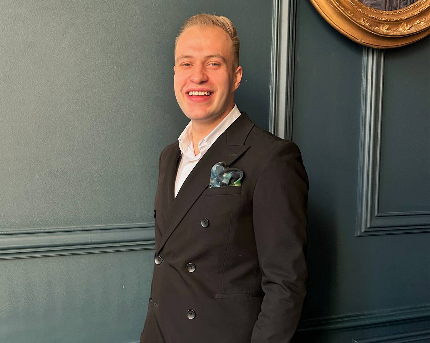 A professional portrait of Maciej, confidently smiling in a contemporary, well-lit interior.