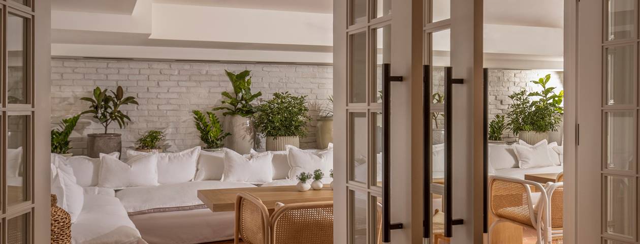 A bright white room adorned with white furniture and lush green plants, creating a serene and minimalist atmosphere.