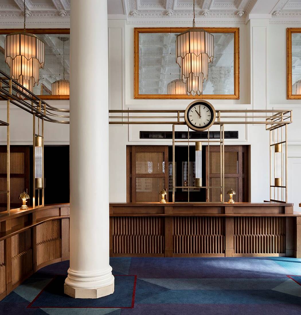 Beautiful wooden reception desk area at Riggs DC in Washington with a marble column and a large clock.
