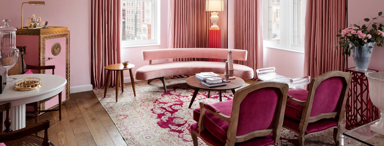 The elegant living room in the Ida McKinley First Lady Suite at Riggs DC featuring classic pink decor and plush seating.