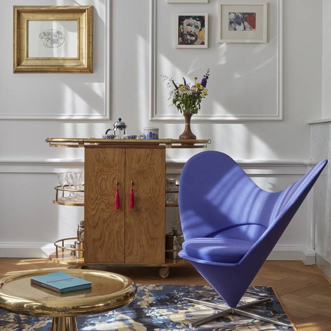 Stylish and unique hotel room interior at Pulitzer Amsterdam with a purple armchair, wooden furniture and cool artwork.