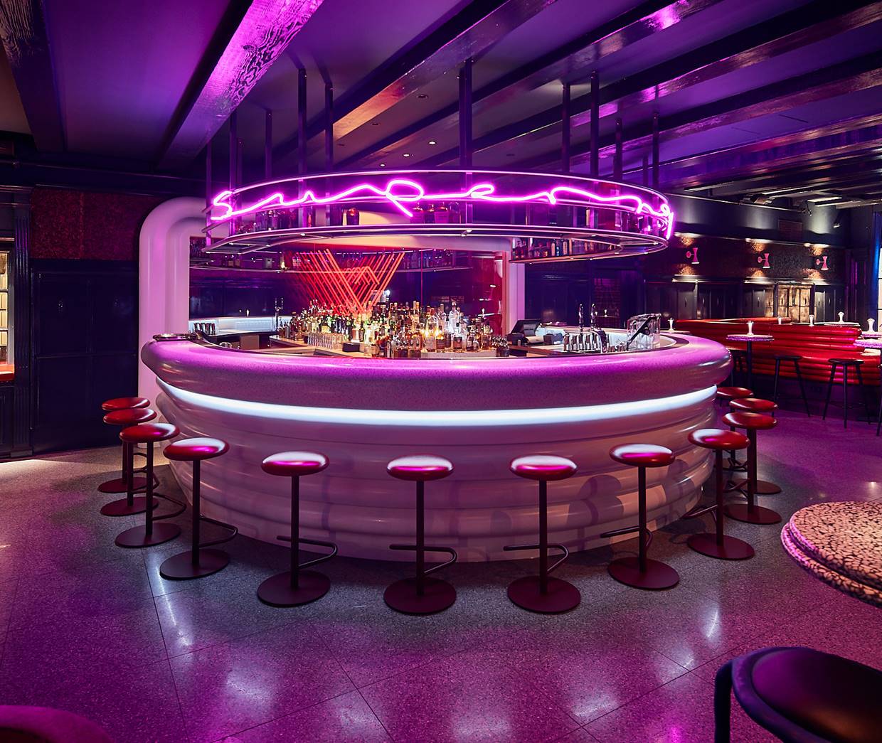 A vibrant bar with contemporary seating, ambient lighting, and a lively atmosphere.