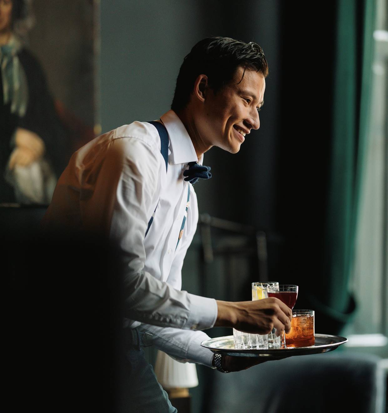 A professional portrait of a well-dressed man, smiling warmly in a modern interior.