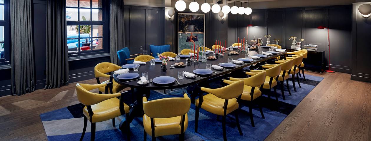 A private dining room with a long table, luxurious chairs, and warm ambient lighting, creating an intimate setting.