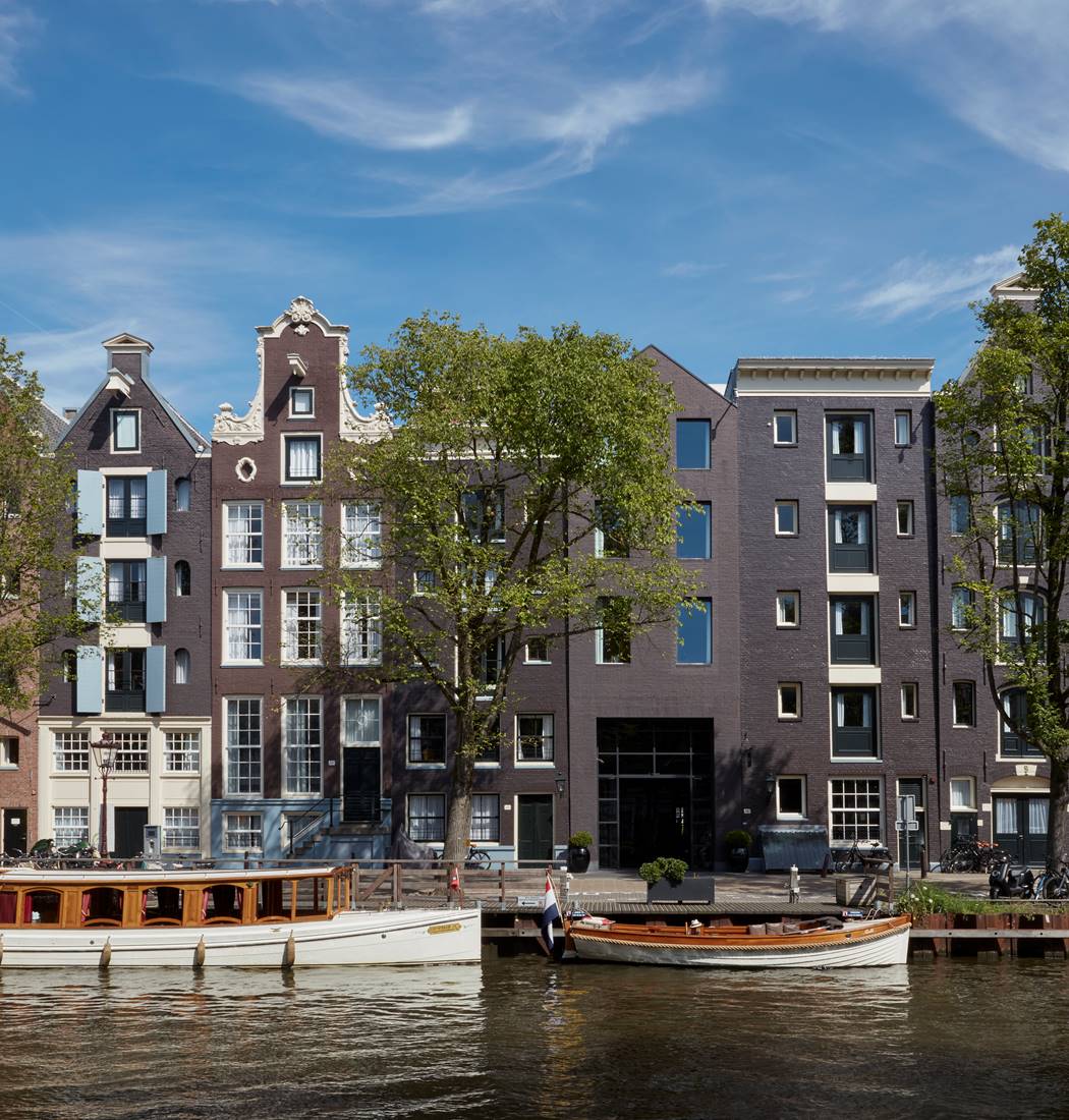 Exterior of the luxury hotel, Pulitzer Amsterdam located by the canal with beautiful greenery around the entrance.