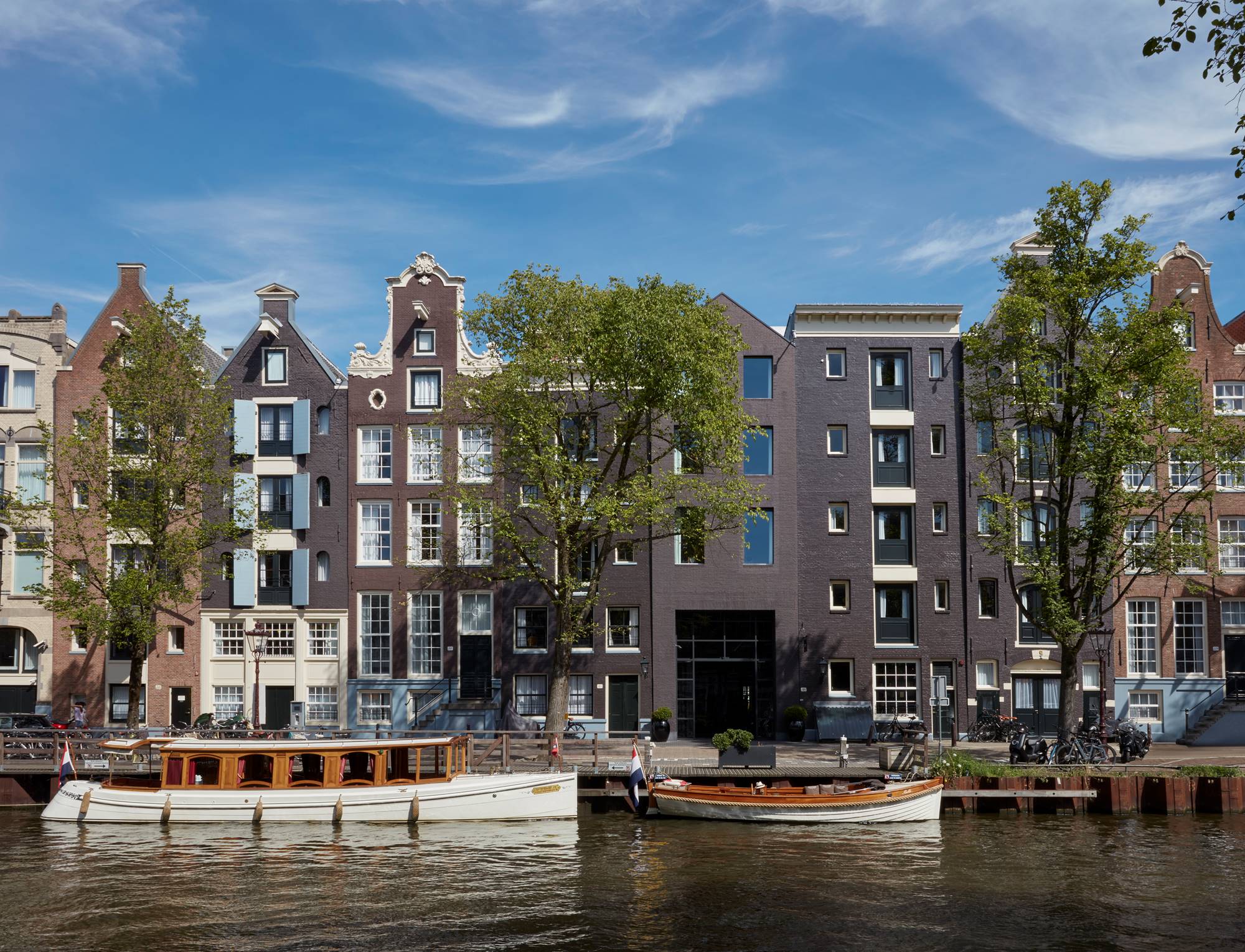 Exterior of the luxury hotel, Pulitzer Amsterdam located by the canal with beautiful greenery around the entrance.