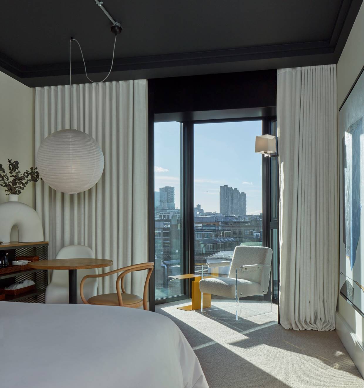 Beautifully lit corner of a modern hotel room showcasing the unique design of Lore Group and a city centre view to London.